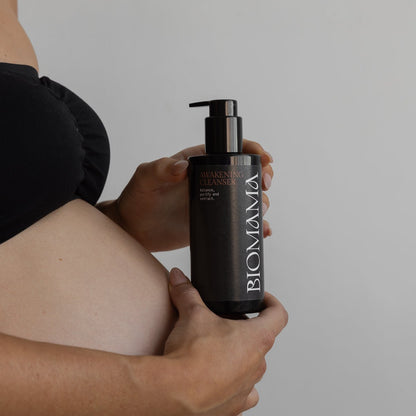 A pregnant woman holding a bottle of Biomama's Awakening Cleanser