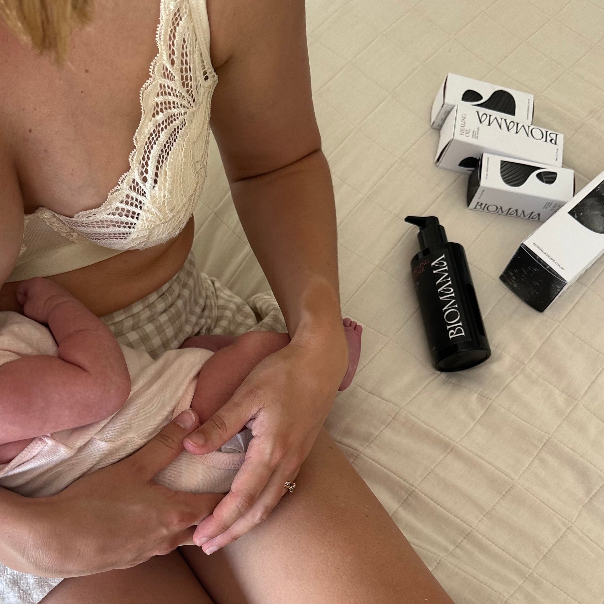 30 year old breastfeeding mother holding baby and sitting next to her Biomama skincare essentials