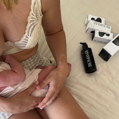 30 year old breastfeeding mother holding baby and sitting next to her Biomama skincare essentials