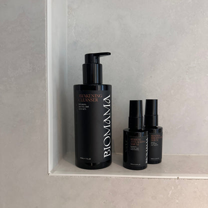 Lifestyle image of Biomama Skincare Awakening Cleanser, Renewal Brightening and Rebirth Anti-Ageing poised on shower shelf